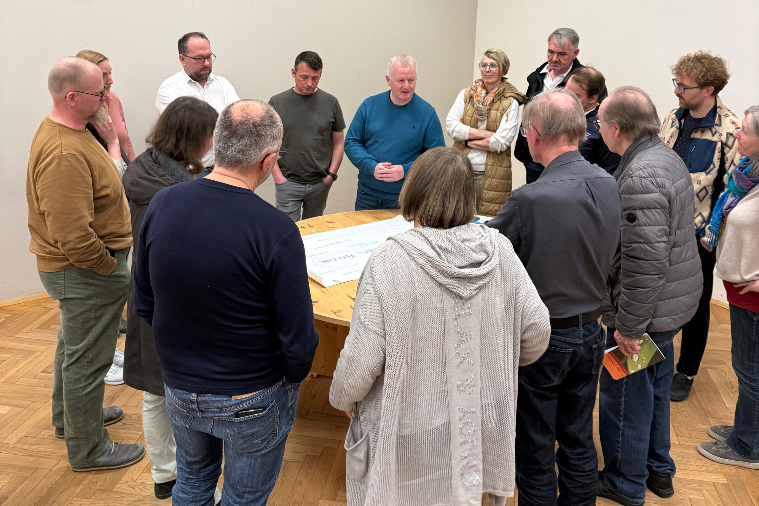 Teilnehmer und Teilnehmerinnen der Veranstaltung diskutieren an einem Thementisch