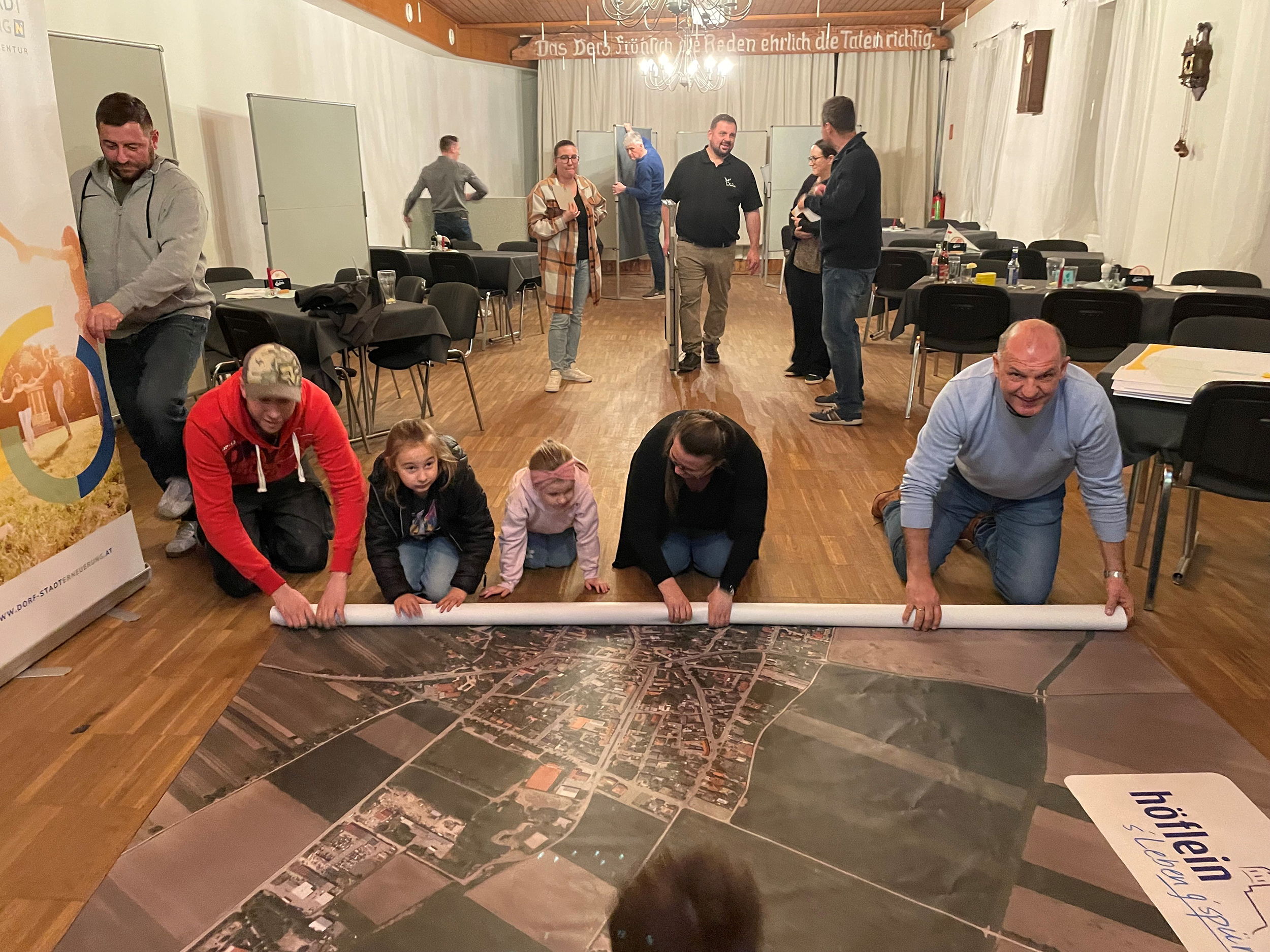 Bürgermeister Otto Auer breitet gemeinsam mit Bürgerinnen und bürgern eine Bodenkarte für den Workshop aus.